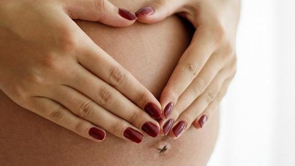 Pregnant woman making a heart shape over her stomach 