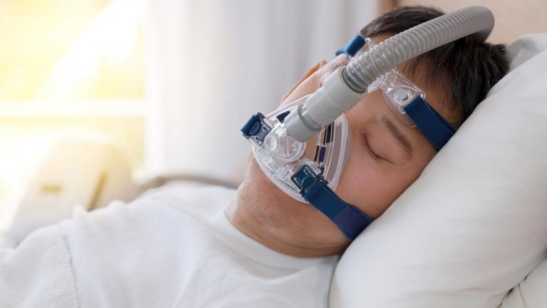A man is shown wearing a device used to treat obstructive sleep apnea. 