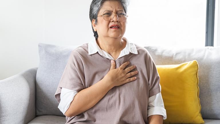 A woman experiencing pain puts her hand to her heart.