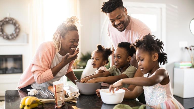 an African American family gathers in the kitchen to cook and laugh