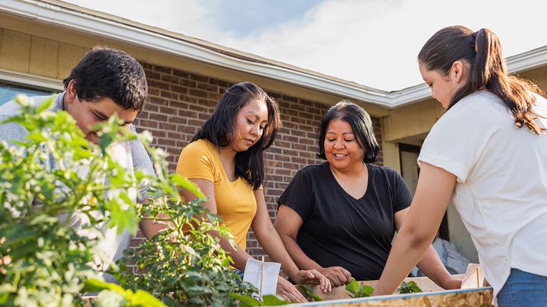 Native American family gathers around an herb planter