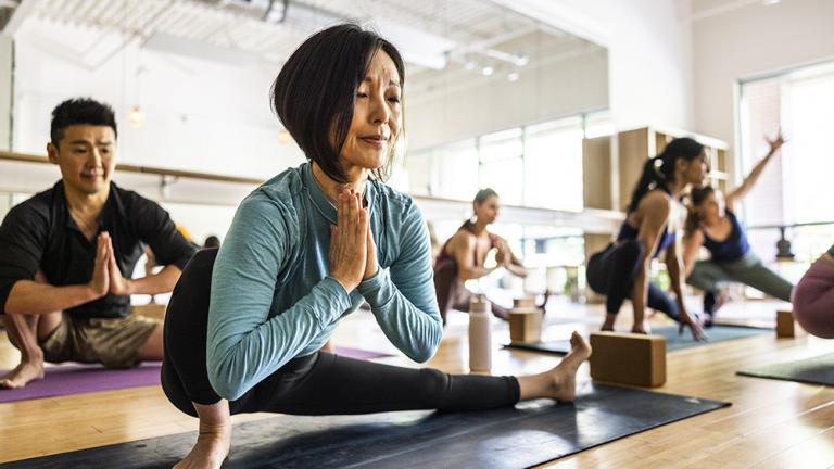 Asian woman and man perform yoga stretches