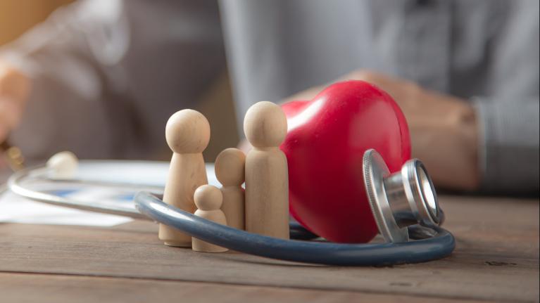 Close up family wooden doll and rad hard and medical stethoscope for insurance planning protection and safety family health concept.