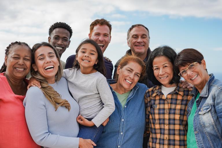 A group of 9 individuals across ages smile for a group photo.
