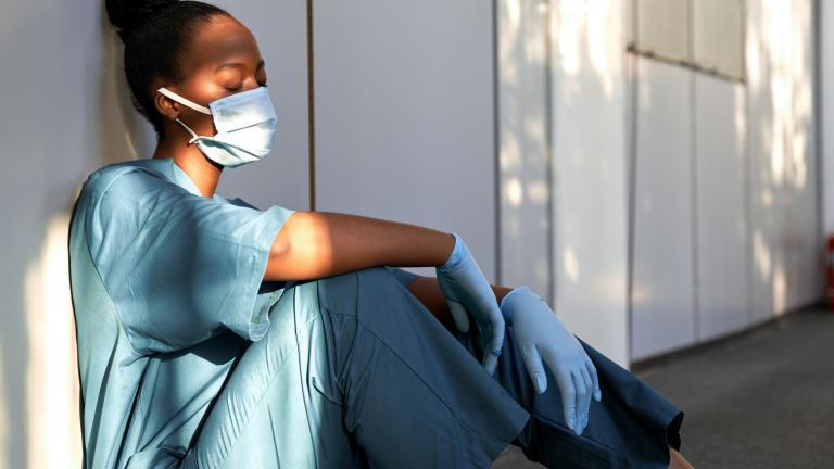 A masked healthcare worker with closed eyes taking a break.  