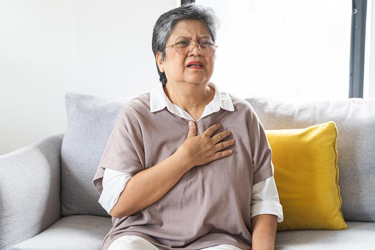 A woman experiencing pain puts her hand to her heart.