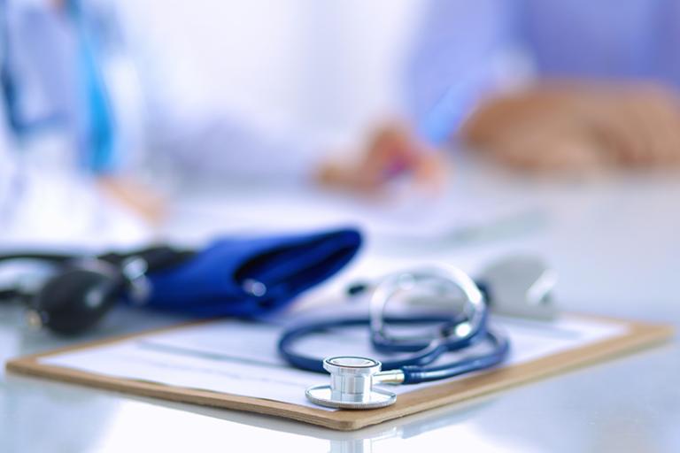 A stethoscope and blood pressure cuff are shown on top of a clipboard.
