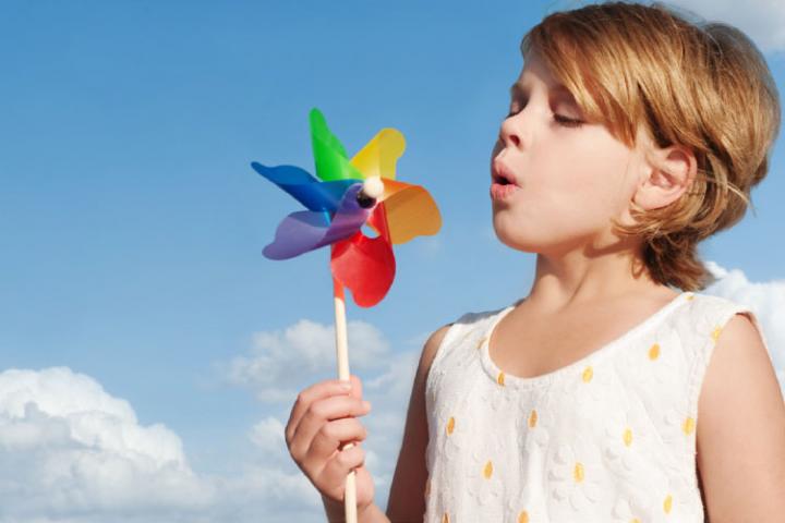 kid blowing on pinwheel