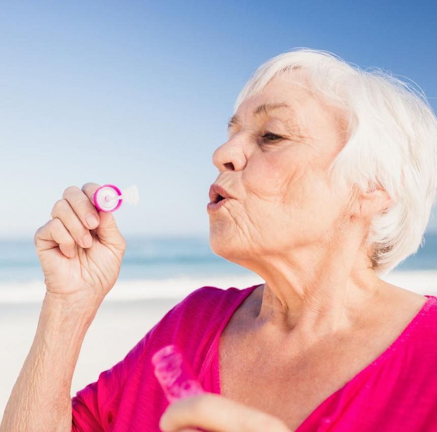 Elderly woman blowing bubbles on the beach