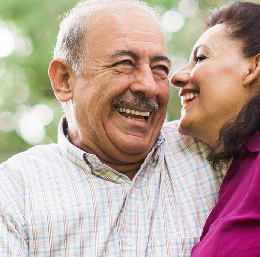 A senior Latin couple laughing and enjoying each other's company in a horizontal waist up shot outdoors